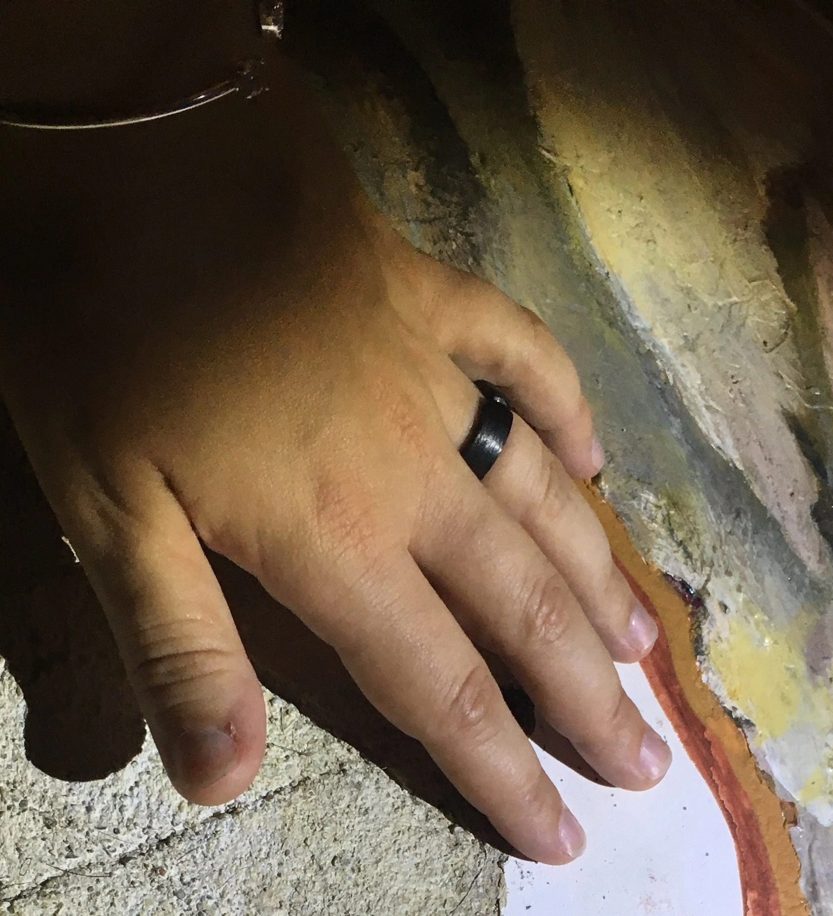 close up of my hand touching an art piece. you can see a black ring on my ring finger